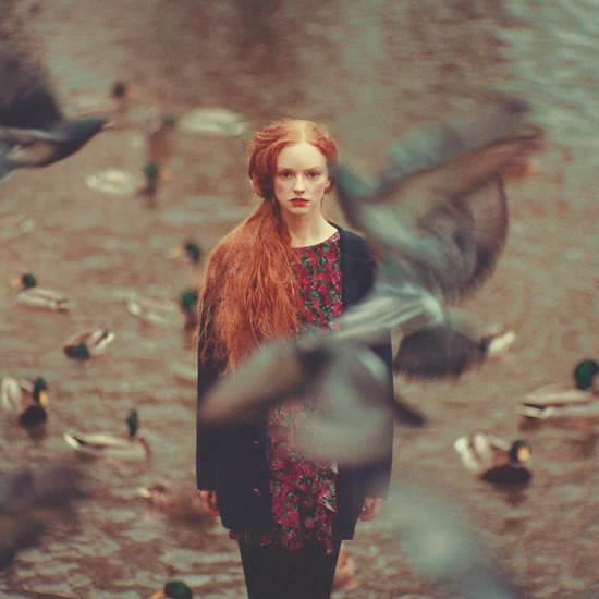 A red-haired woman surrounded by flying birds in a hazy, dreamlike scene, from 'A Fantasy World Made by Oleg Oprisco'