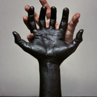 Sculpture of a black textured hand against a grey background