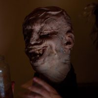 Sculpture of a distorted head with a melting texture under dark ambient lighting