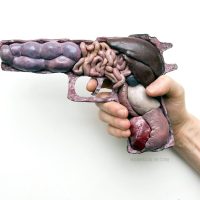 A sculpture of a hand holding a gun made of fleshy, organic material, titled 'Anatomy of War'