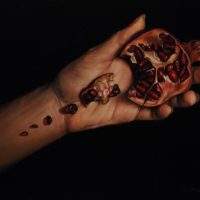A close-up photo of a hand holding an opened pomegranate with dripping juice, from 'Gothic Portraits and Still Life'