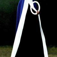 Photograph of a person in a white and blue draped robe forming a circular loop shape