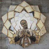 Circular mixed-media wall artwork with a figure at its center and a radiating patterned border