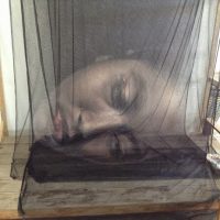 Ghostly photograph of a reclining figure obscured by translucent fabric