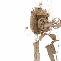 Sepia-toned photograph of a whimsical mechanical sculpture with wheeled legs and gears