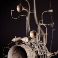 Photograph of a dark mechanical sculpture with round bulb shapes and a horn form