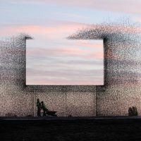Sculpture of an abstract wire mesh window frame silhouette against a pink sunset sky