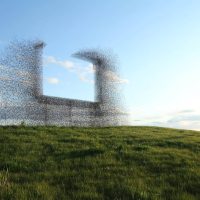 Sculpture of an abstract wire mesh silhouette figure against a green field and blue sky
