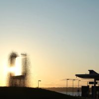 Sculpture of an abstract wire mesh silhouette figure against a sunset sky