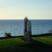Sculpture of an abstract wire mesh silhouette figure by the seaside