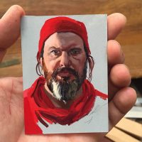 Illustrated portrait of a man with a red beard and hat, held in a hand
