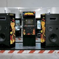 Gallery installation of large black speaker towers arranged in a room