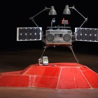 A boombox-shaped sculpture mounted on a red, lunar-lander-like pedestal, from 'Boombox Retrospective'