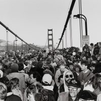 Black-and-white archival photograph of a crowd gathered on the Golden Gate Bridge