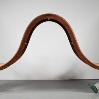 Two people seated at opposite ends of a curved, wave-shaped table, from 'The Avoid Conversation Table' by Michael Beitz