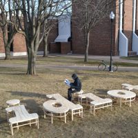 Aerial view of curved wooden sculptural benches by Michael Beitz installed in a park near a brick building