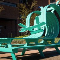 Teal sculptural picnic table with a curved, wave-like bench by Michael Beitz, installed outdoors