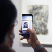 Visitor photographing one of Abdolhossein Pazoki's drawings on display at Aliha Gallery