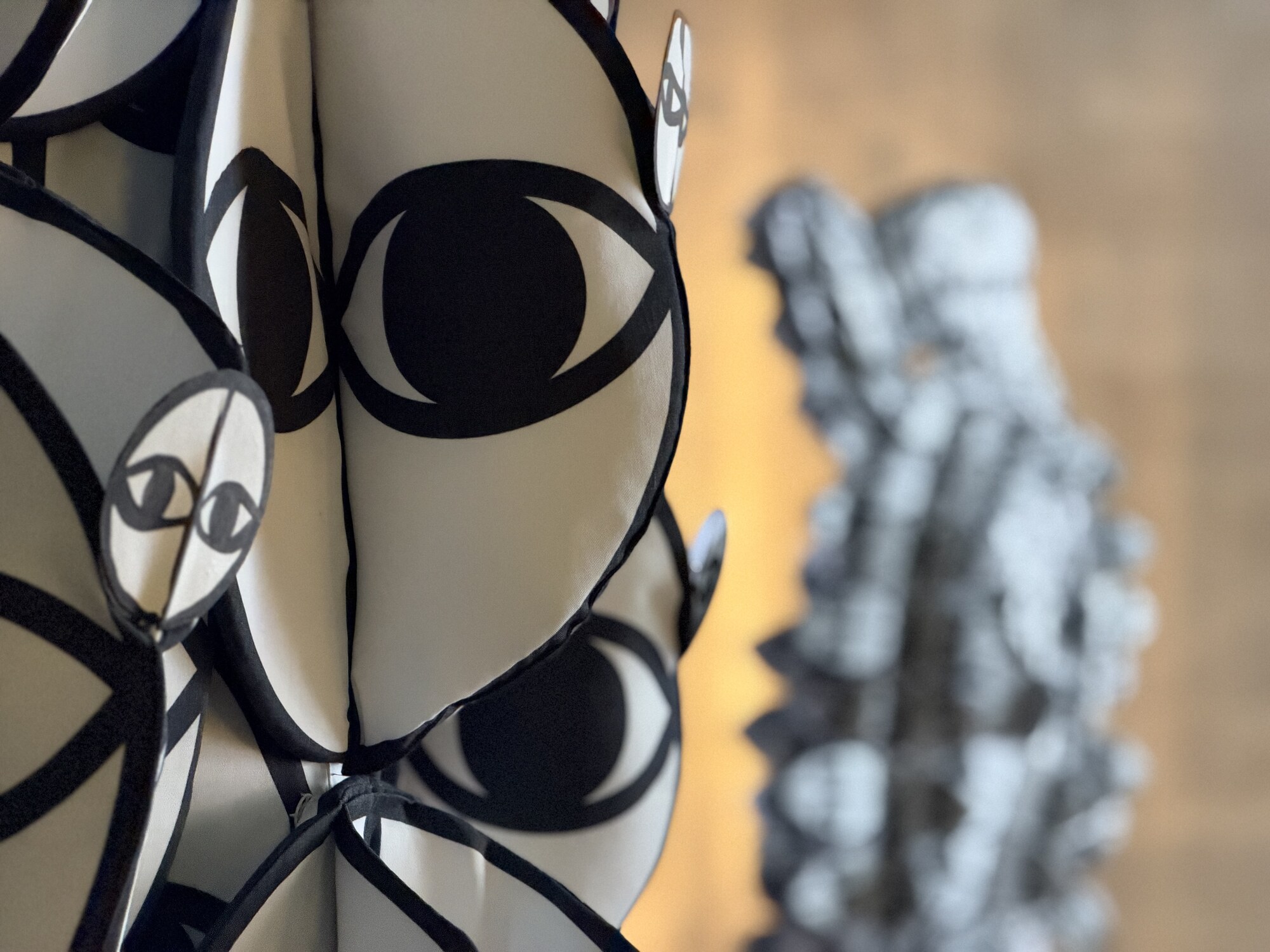 Close-up of a sculpture covered in stylised black-and-white eyes