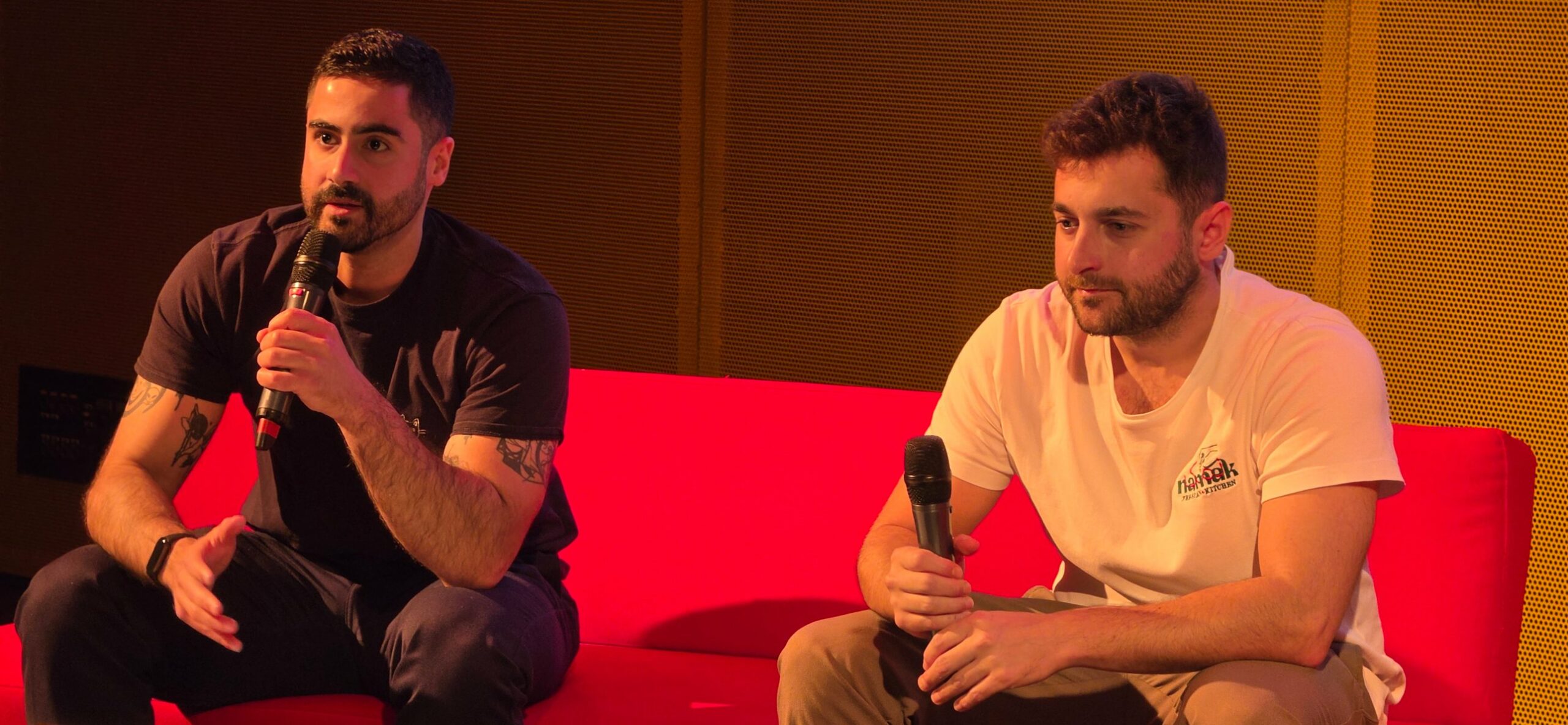 Namak’s two co-founders seated on a red sofa, speaking into microphones