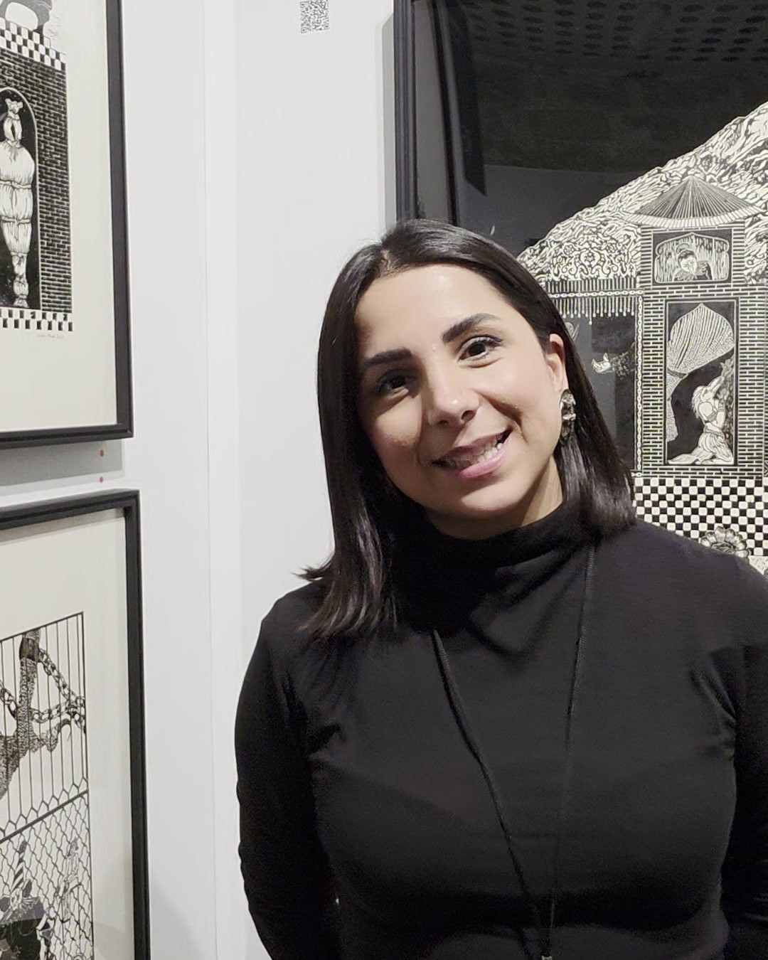 Tannaz Keshavarzian, directrice de la Galerie Keshavarzian, devant des linogravures en noir et blanc de Mojdeh Atrak à MENART Fair, Paris